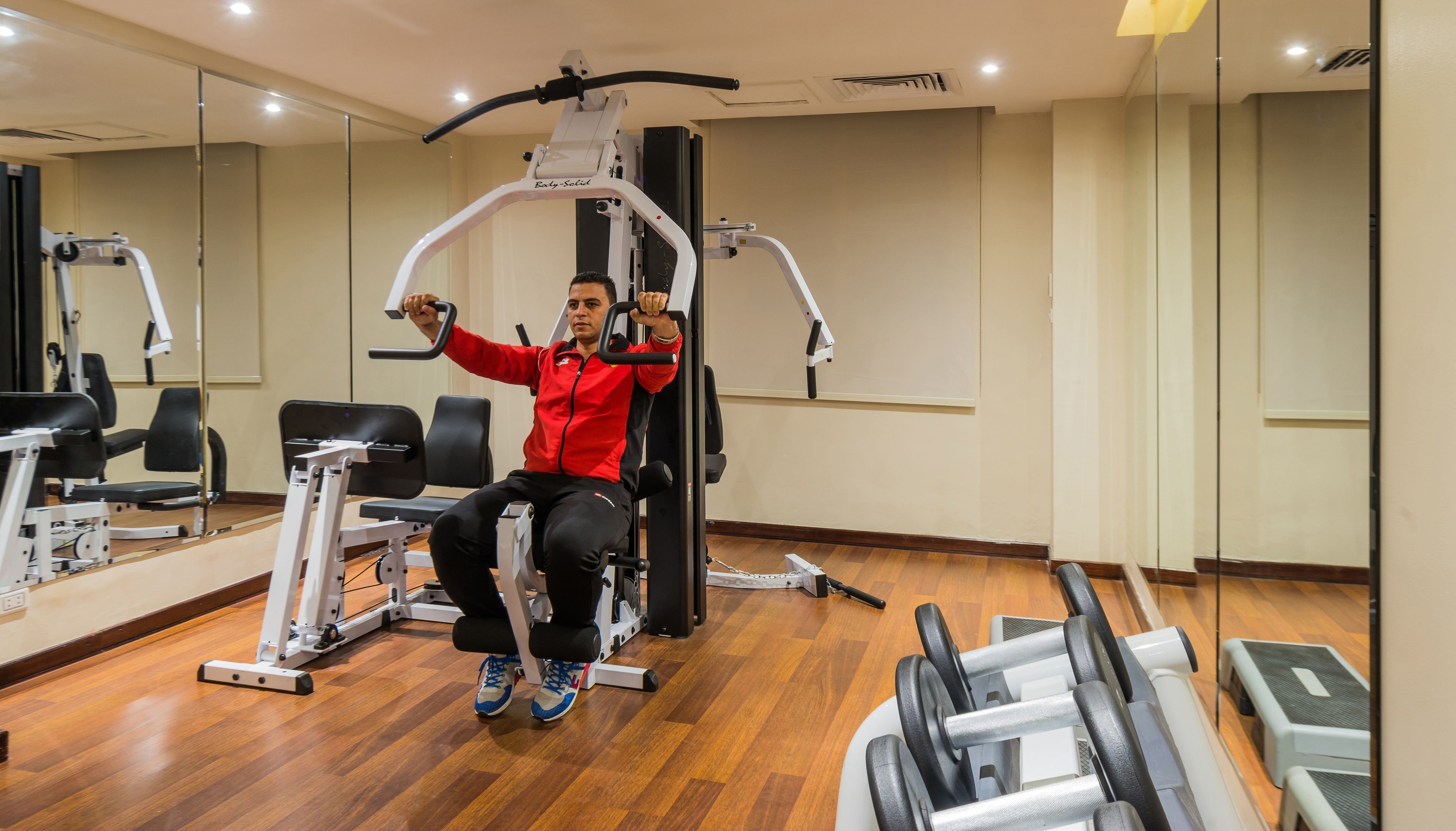 Un gimnasio con equipo de ejercicio, que incluye una máquina de remo sentado y mancuernas.