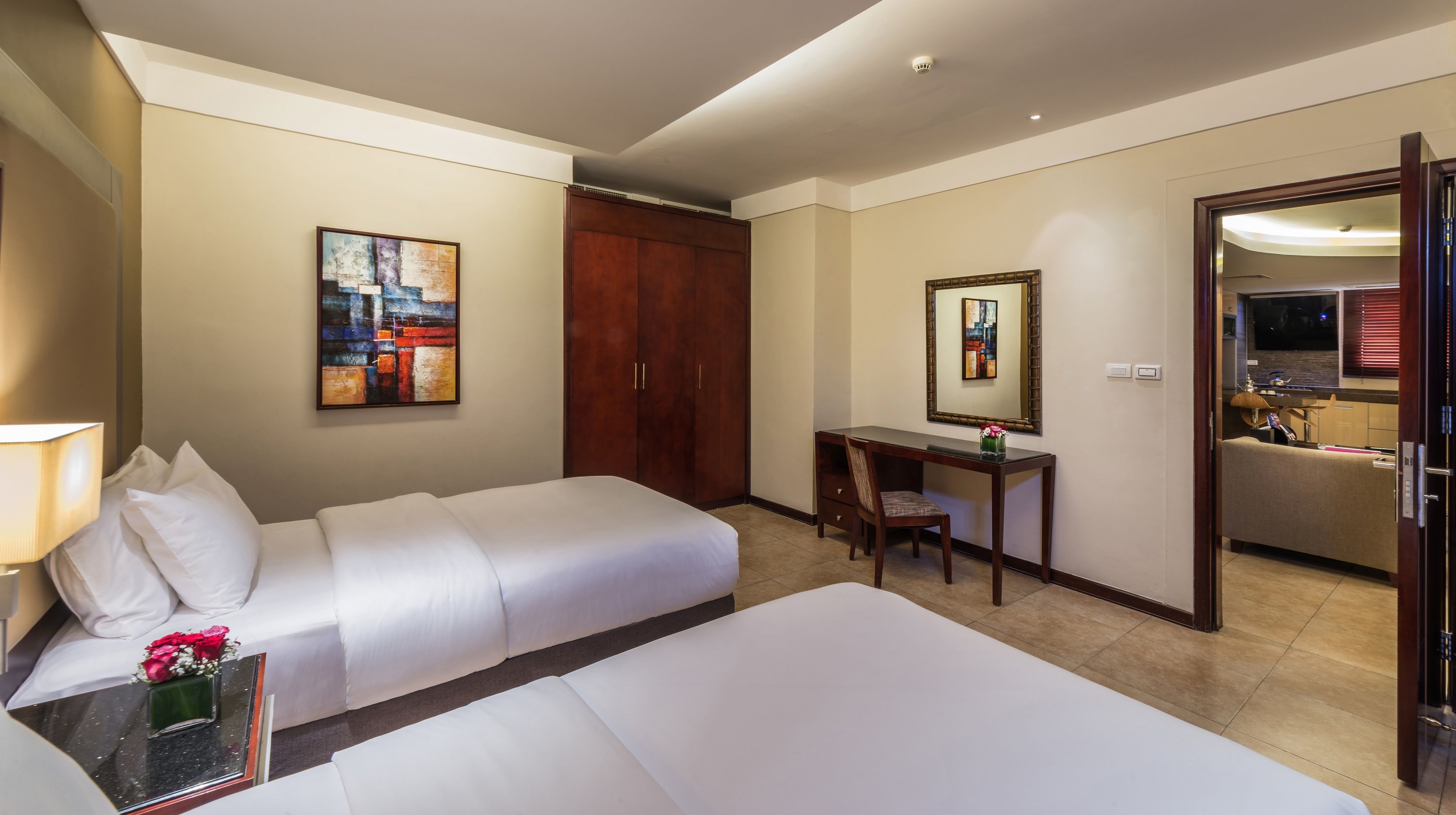 A hotel room with a bed, a desk, a chair, a wardrobe, and a bathroom visible through an open door.