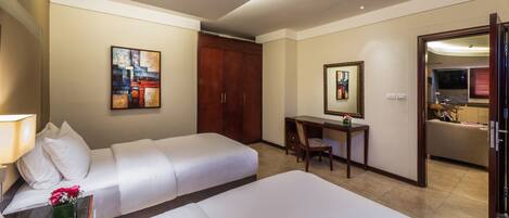 Une chambre d’hôtel comprenant un lit, un bureau, une chaise, une armoire et une salle de bain visible à travers une porte ouverte.