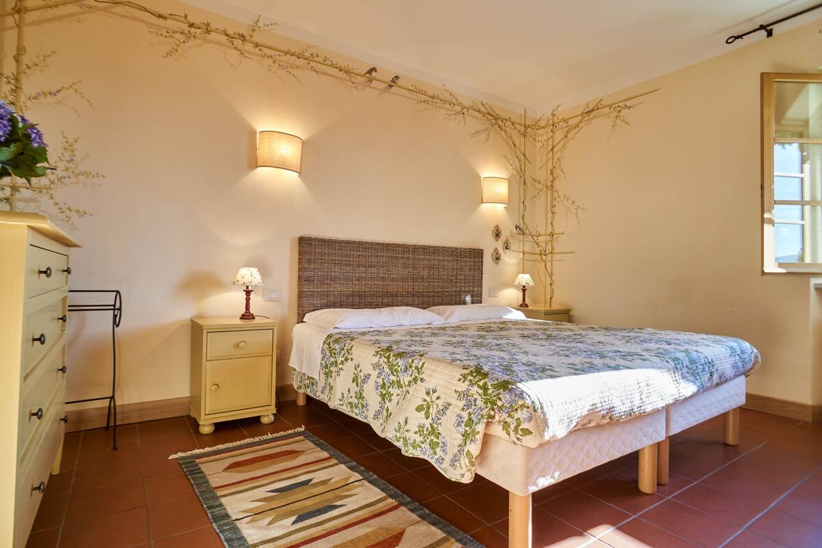 Een slaapkamer met een bed, nachtkastjes, een dressoir en een spiegel.