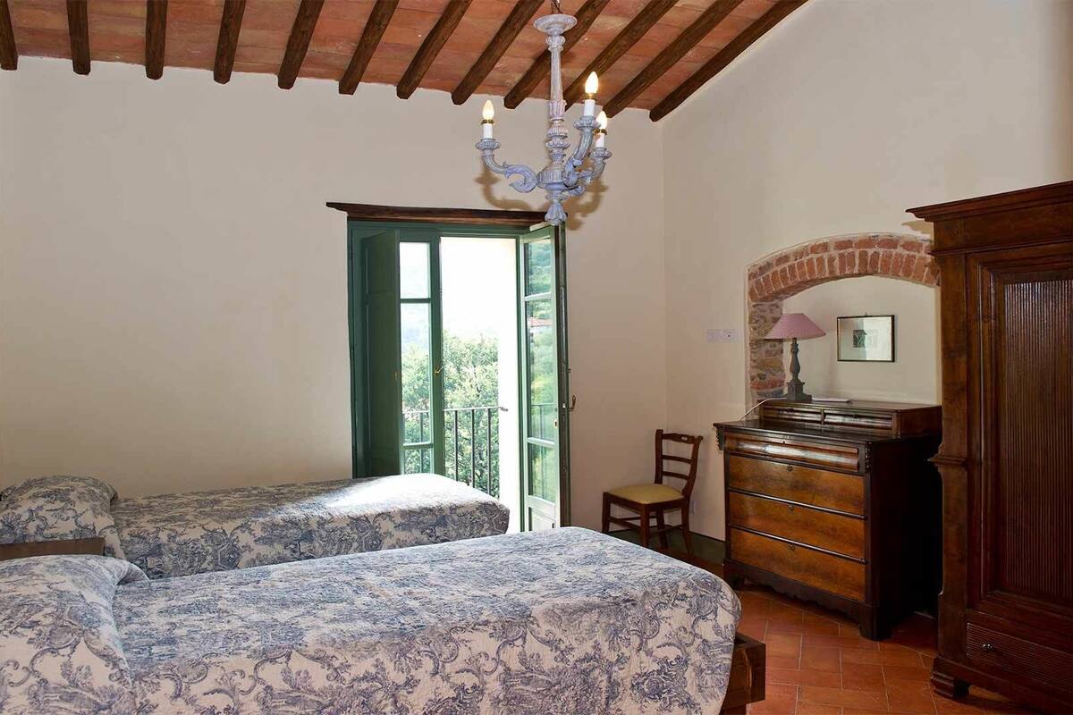 Een slaapkamer met twee bedden, een kaptafel, een stoel en een kroonluchter.