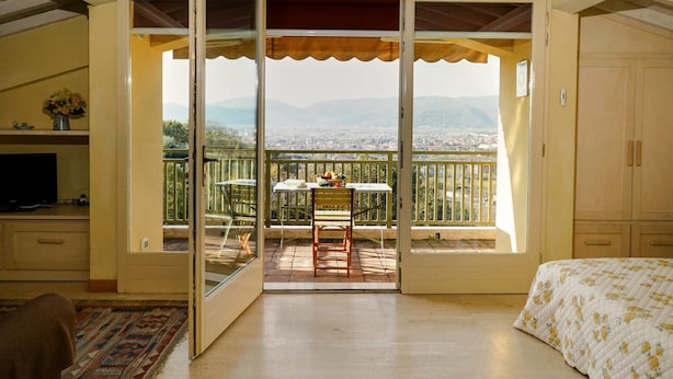 A bedroom with a balcony, a bed, a TV, and a rug. - Agriturismo Monteverde (Castelnuovo Magra)