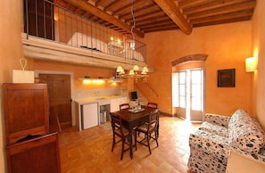 Una cocina acogedora con comedor, muebles de madera y una escalera que sube a una buhardilla.