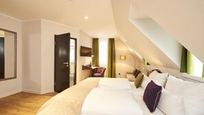 A bedroom with a large bed, a desk, a chair, a TV, and a window with curtains. - Hotel Hauser (Nuremberg)