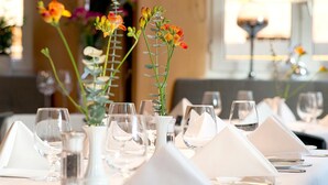 A dining table set with white tablecloths, glassware, and a floral centerpiece. - Hotel Hauser (Nuremberg)