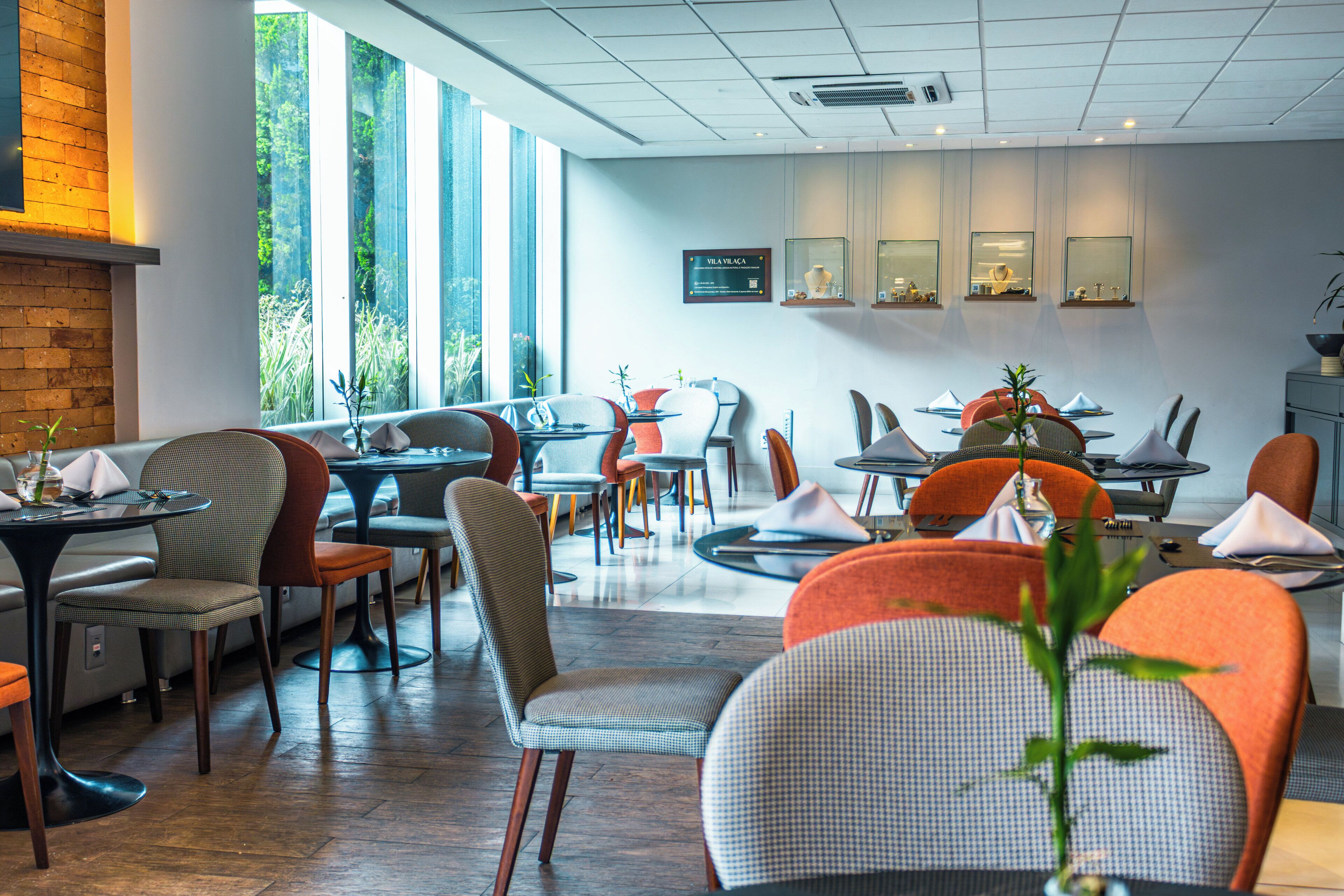 Un restaurante moderno con varias zonas de estar, ventanas amplias y un diseño limpio y contemporáneo.