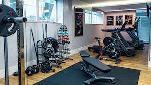 A gym with weightlifting equipment, a bench, and cardio machines.