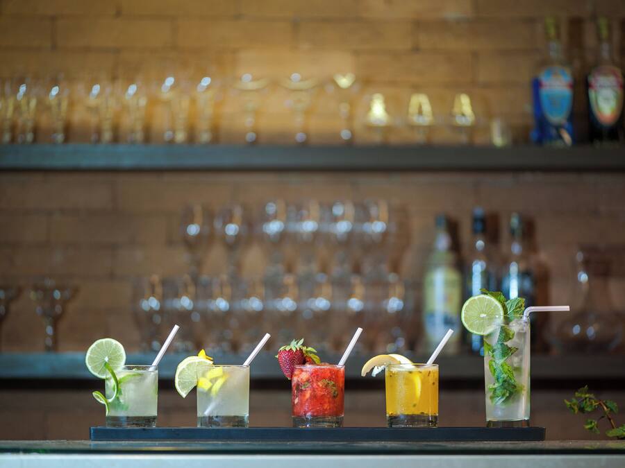 A bar counter with a selection of drinks and a backdrop of neatly arranged glasses.