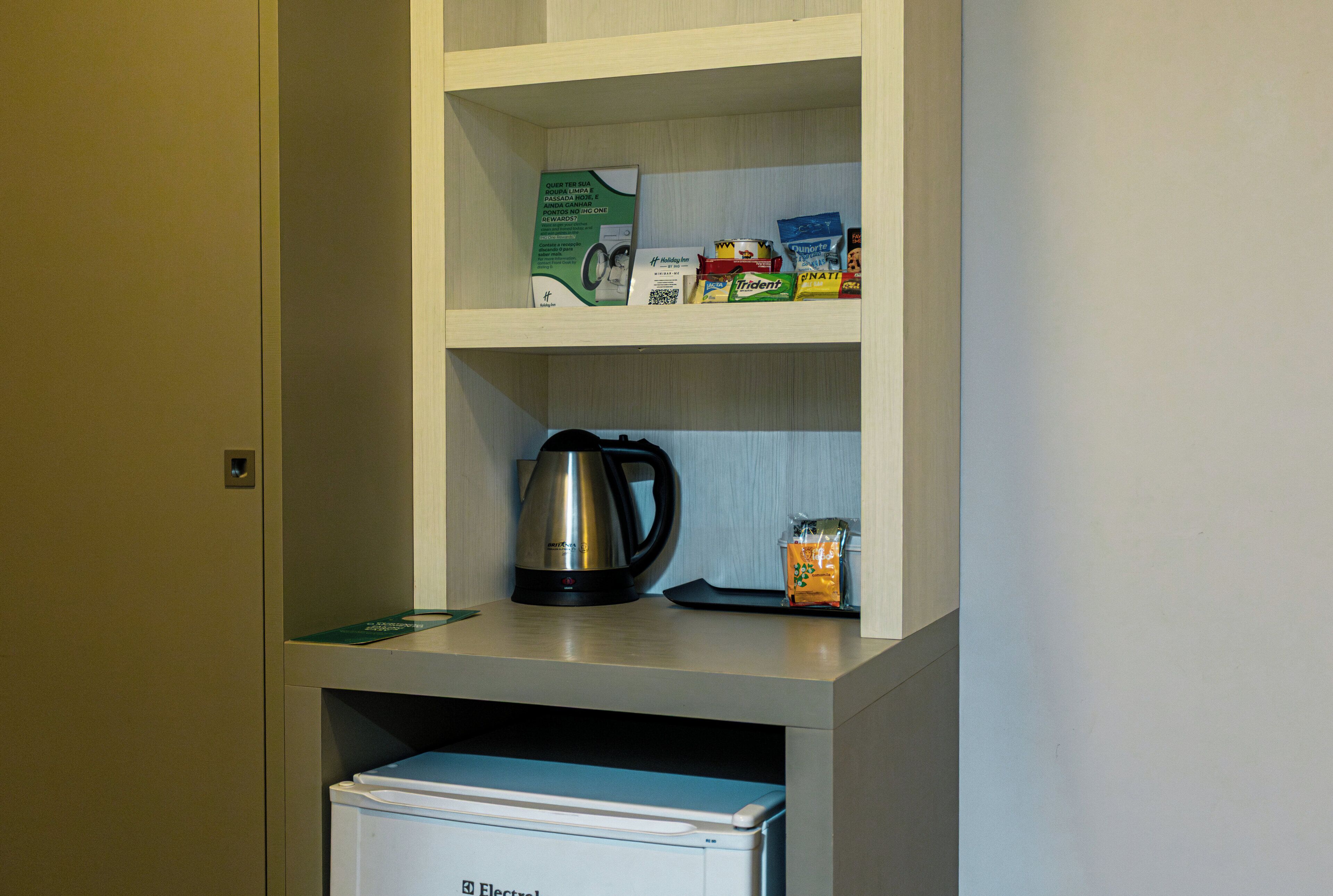 A kitchenette with a coffee maker, a kettle, and a mini-fridge.