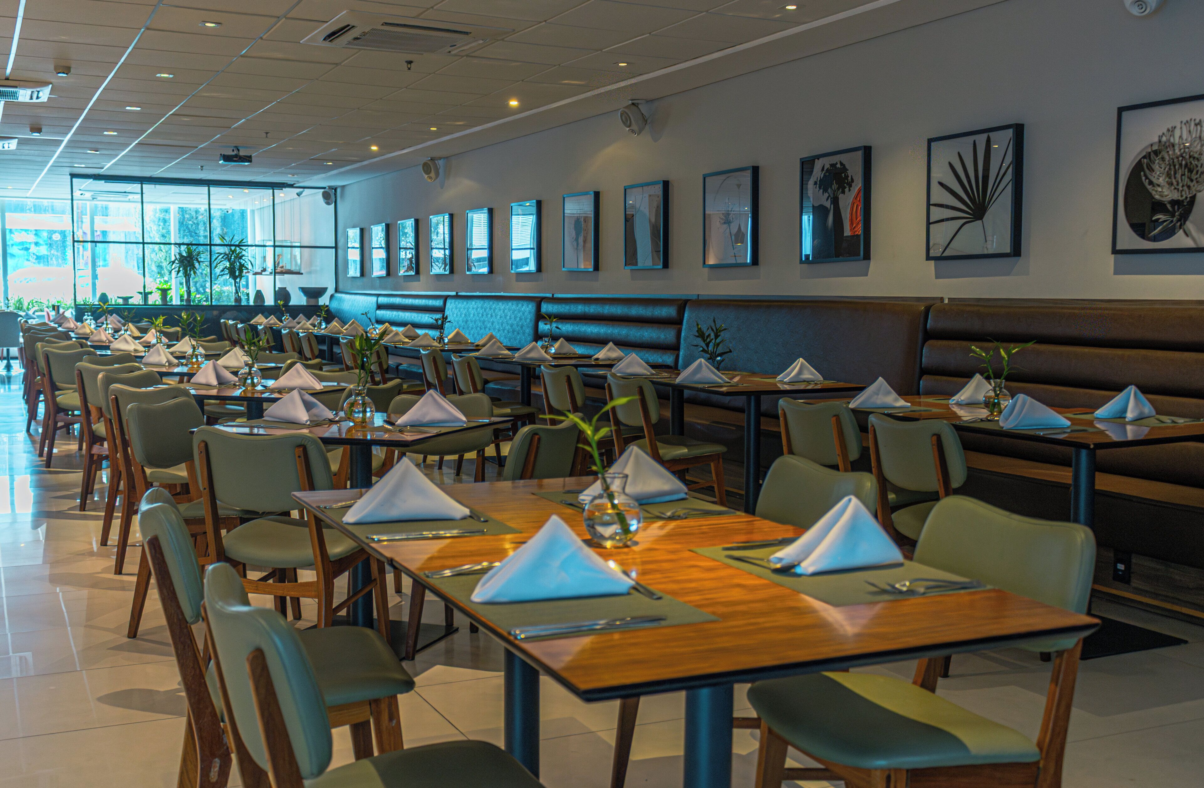 A restaurant with multiple tables and booths, arranged in rows, with chairs and place settings.