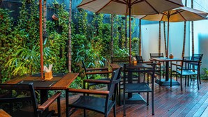 An outdoor dining area with wooden tables and chairs, surrounded by lush greenery and bamboo structures. - Holiday Inn Belo Horizonte Savassi by IHG (Belo Horizonte)