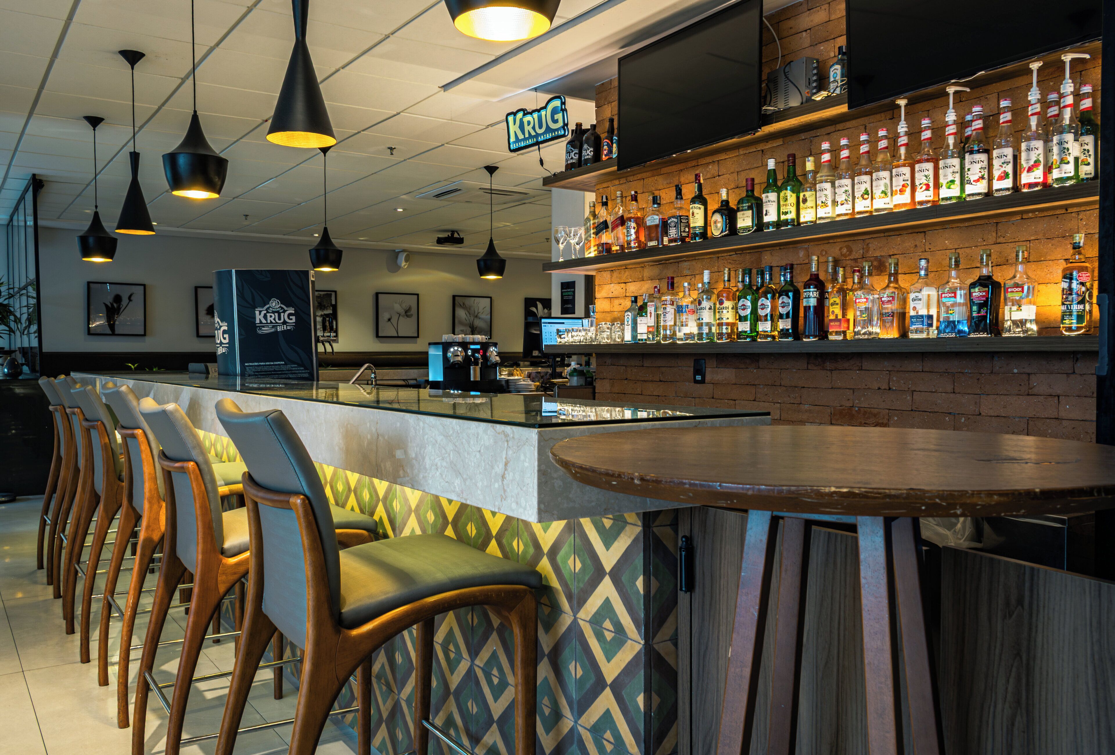 Un espace bar avec un comptoir, plusieurs chaises et une variété de bouteilles d’alcool.