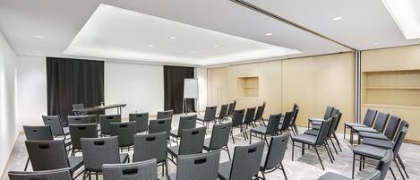 A conference room with rows of chairs, a table, and a projection screen.