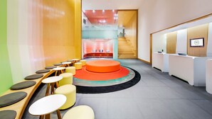 Un área de recepción moderna con un espacio de estar central, una escalera y un mostrador de recepción.