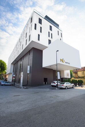 A modern hotel with a prominent 'MU HOTEL' sign, a clean facade, and a parking area with several cars. - MÙ Hotel (Ipoh)
