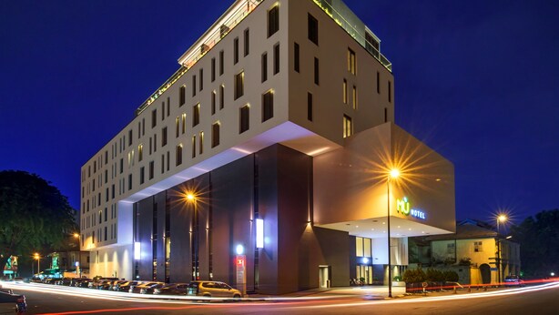 Un hotel moderno con una entrada destacada, varios pisos y una fachada bien iluminada.