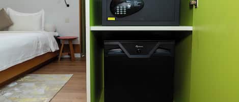 Una habitación pequeña con cama, un taburete, microondas y refrigerador.