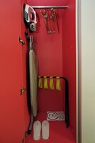 Un baño rojo con ducha, plancha y perchero para toallas.