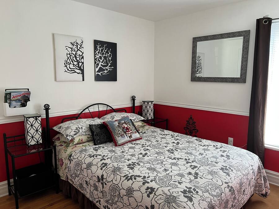 Un dormitorio con cama, mesita de noche, espejo y decoración en la pared.