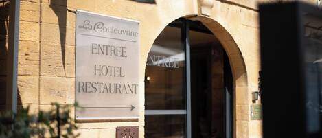 A sign for La Couleuvrine, an entree hotel and restaurant with an arched entrance.