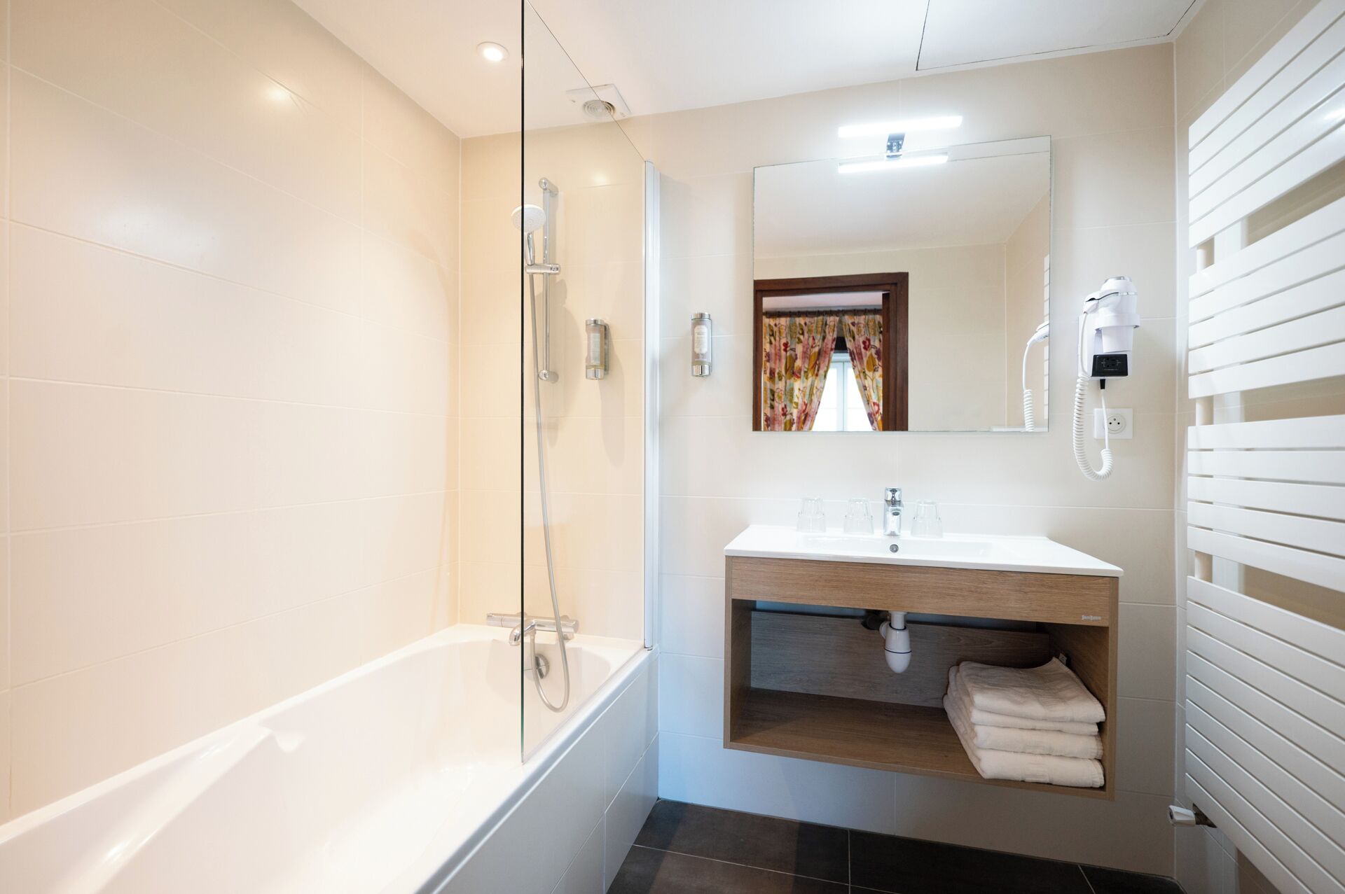 A modern bathroom with a glass-enclosed shower, a vanity with a mirror, and a towel rack.