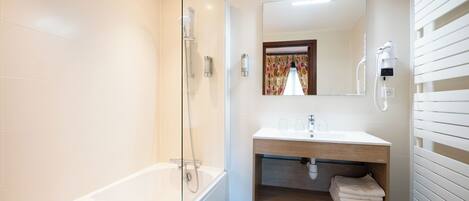 A modern bathroom with a glass-enclosed shower, a vanity with a mirror, and a towel rack.
