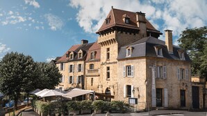 Een historisch gebouw van steen met een opvallende toren, een restaurant en een duidelijke ingang.