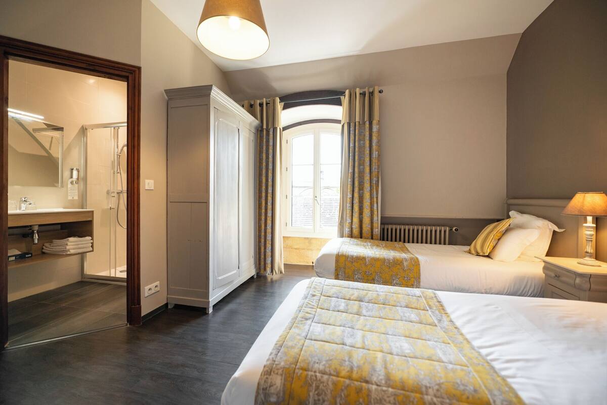 A hotel room with a bed, a wardrobe, a bathroom, and a window with curtains.