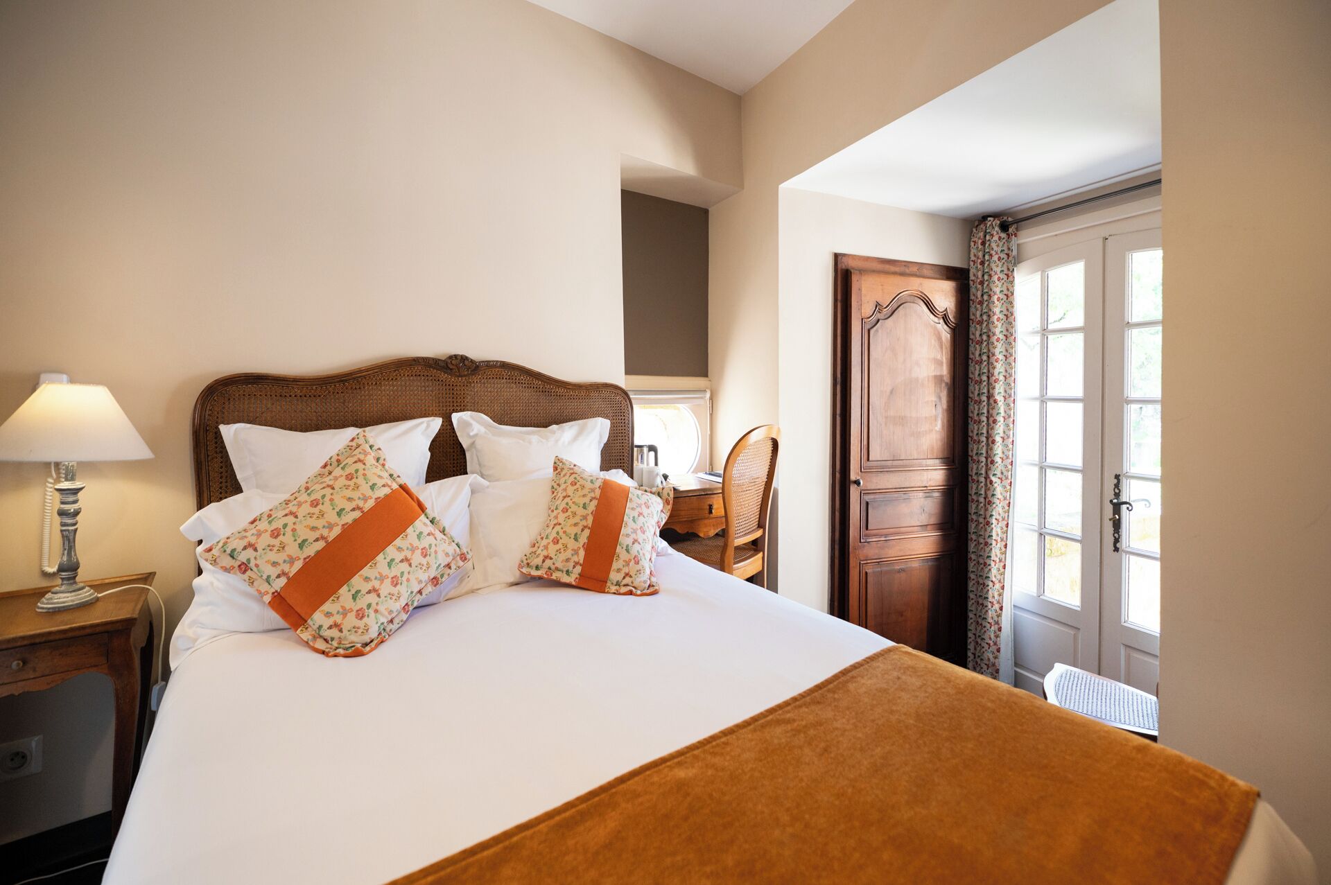 Une chambre d’hôtel avec un lit, un bureau, une chaise, une lampe et une porte.