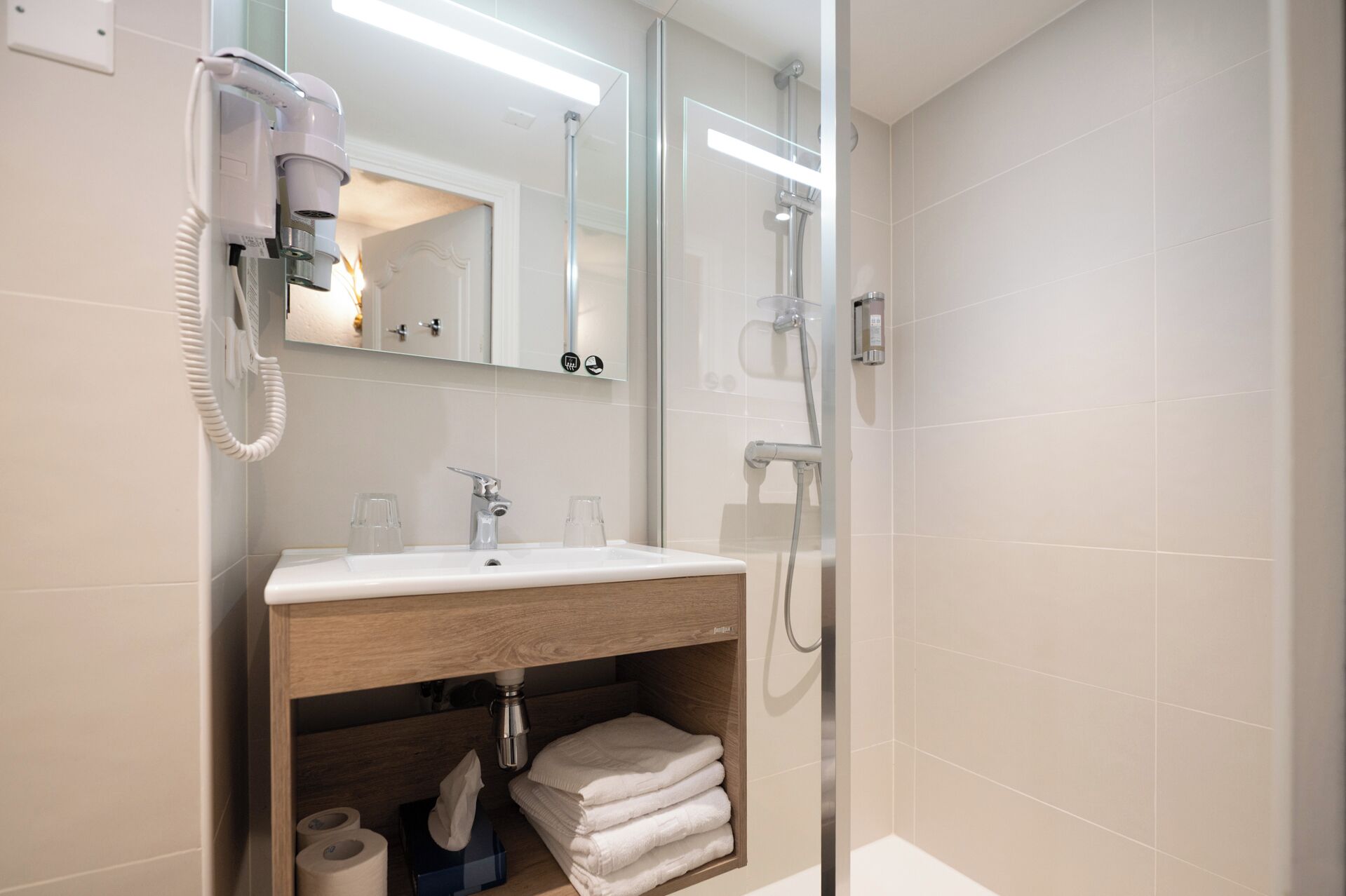Baño con lavabo, espejo, secador de pelo y ducha.