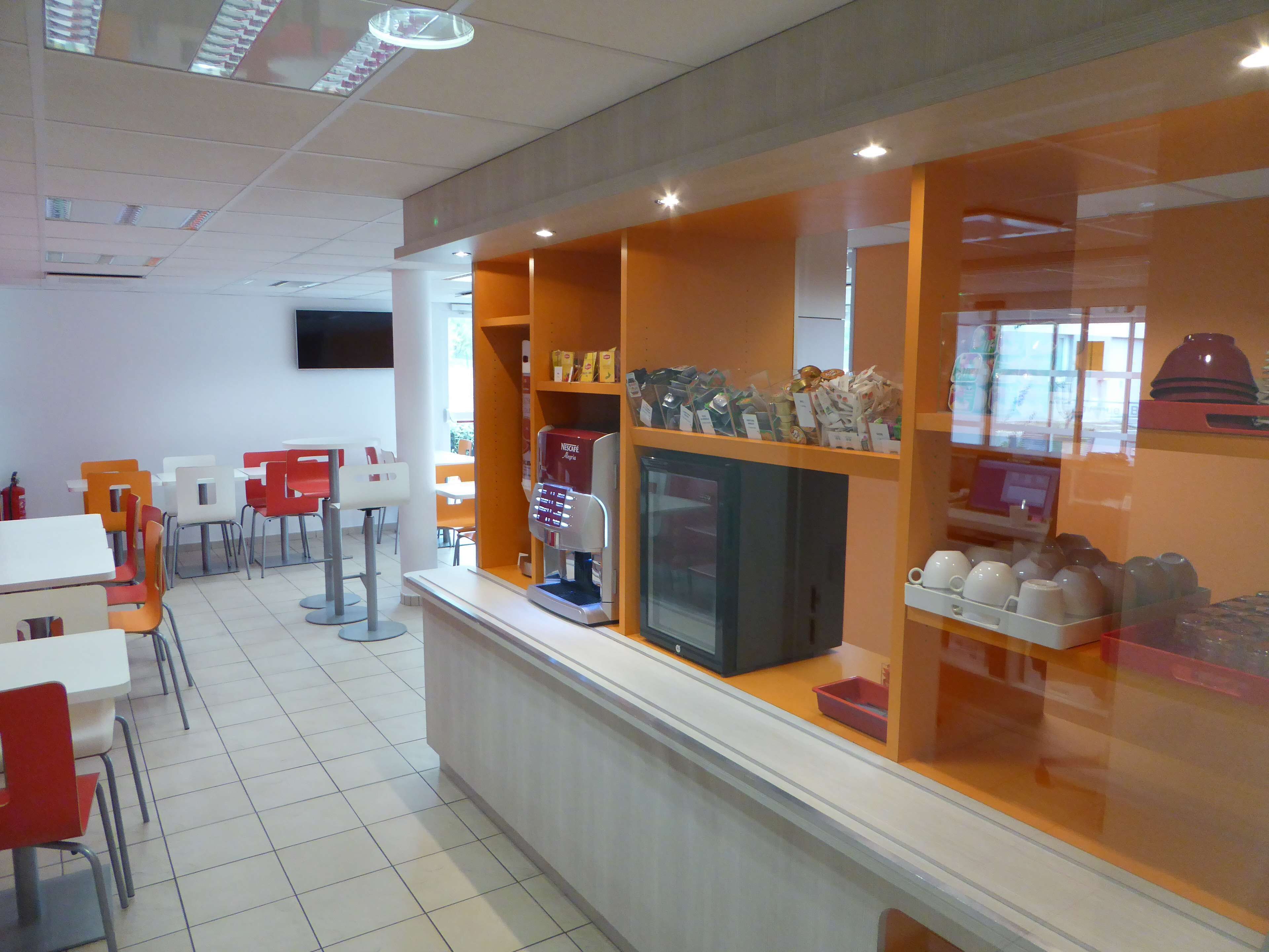 Ein Café mit Theke, Sitzgelegenheiten und einer Kaffeemaschine.