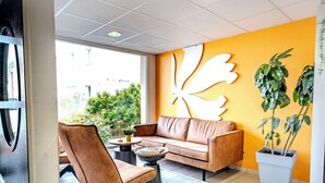 A modern reception area with a leather sofa, a coffee table, and a large wall art piece.