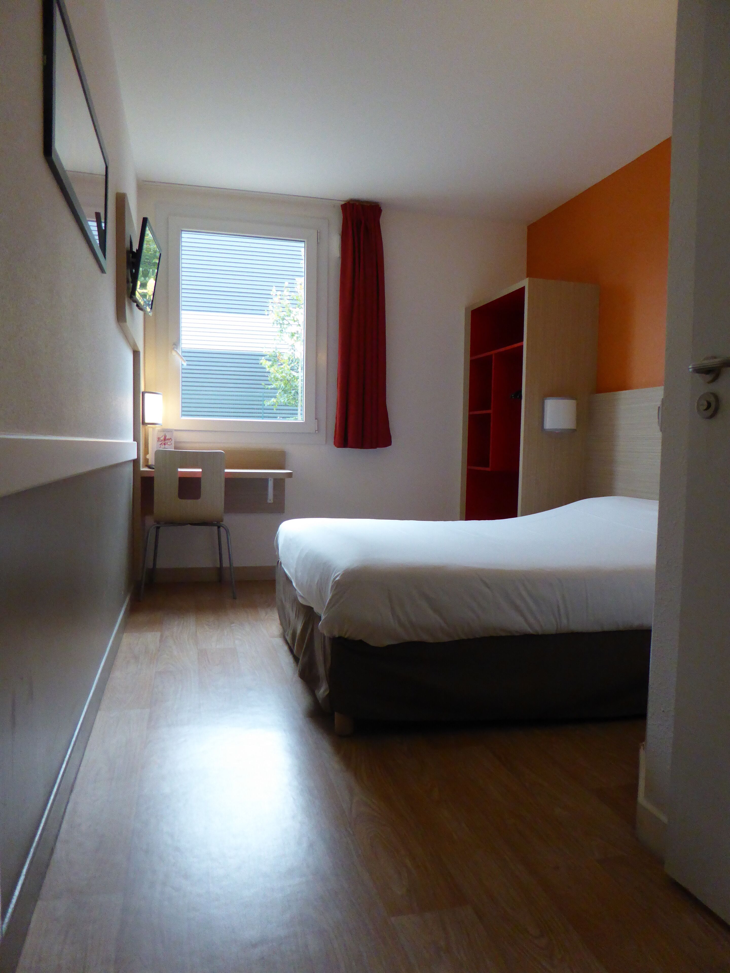 Een slaapkamer met een bed, een bureau en een stoel.