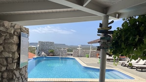 Un espace piscine avec des chaises longues, un mur en pierre et une vue sur le paysage.