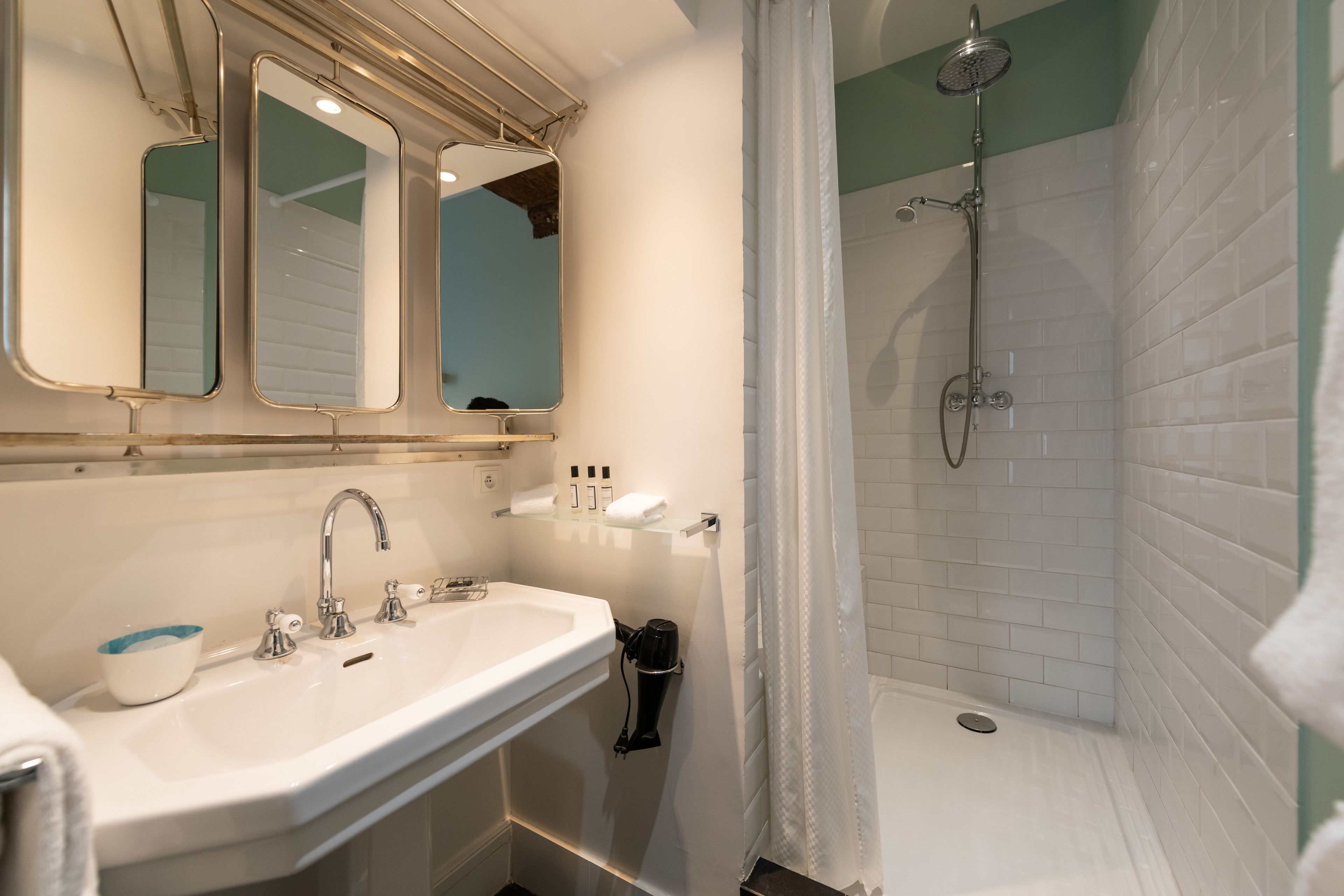 Une salle de bain équipée d’un lavabo, de miroirs, d’une douche et d’un porte-serviettes.