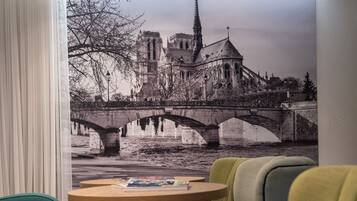 Una habitación con un mural de un puente histórico y una catedral, una mesa de madera con una computadora portátil y una silla verde.