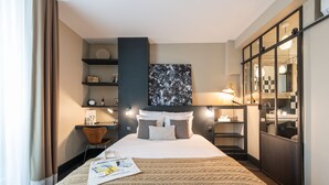 A hotel room with a large bed, a bedside table, a mirror, and a wardrobe. - 1er Etage Marais (Paris)