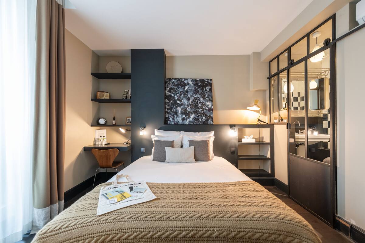 Une chambre d’hôtel avec un grand lit, une table de chevet, un miroir et une armoire.