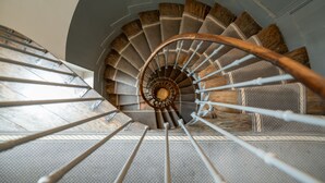 A spiral staircase with wooden steps and metal railings. - 1er Etage Marais (Paris)