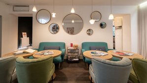 A modern room with teal chairs, wooden tables, and multiple mirrors on the walls. - 1er Etage Marais (Paris)
