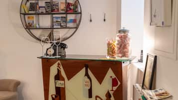 A room with a wooden cabinet featuring a geometric design, a round bookshelf, and a small table with a jar of candies.