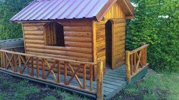 A wooden cabin with a metal roof, a porch, and a small window.