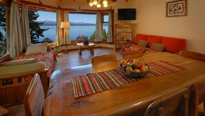 Un salón acogedor con una mesa de comedor de madera, un sofá y vistas a un lago.
