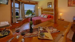 Una habitación de hotel con una cama, una mesa de comedor con comida y bebidas, y vistas al exterior.