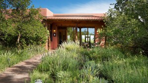 A building with a covered patio area, surrounded by lush greenery and a paved pathway leading to the entrance. - Blue Lake Ranch (Hesperus)