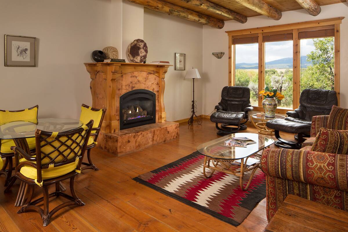Un salon chaleureux avec une cheminée, des meubles en bois et une vue sur l’extérieur.
