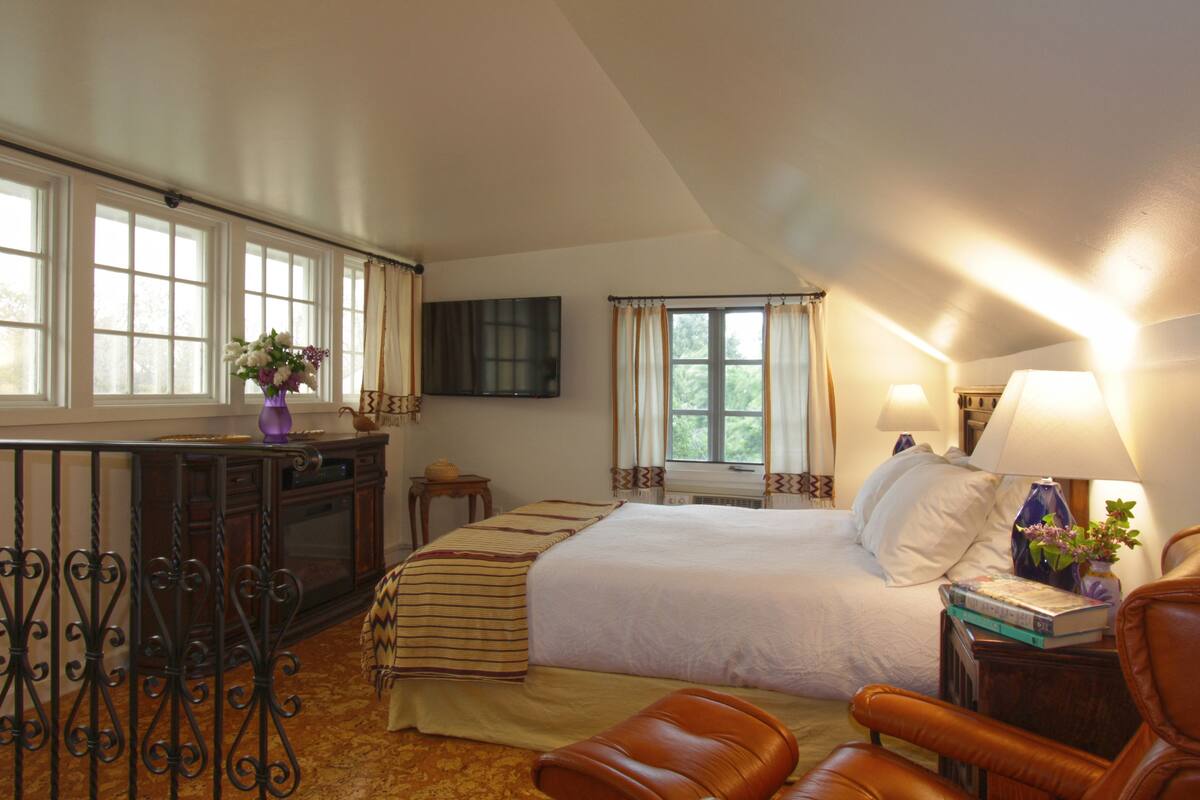 Une chambre avec un grand lit, un bureau, une chaise et un téléviseur fixé au mur.