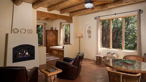 A cozy living room with a fireplace, leather chairs, a dining table, and large windows offering a view of the outdoors. - Blue Lake Ranch (Hesperus)