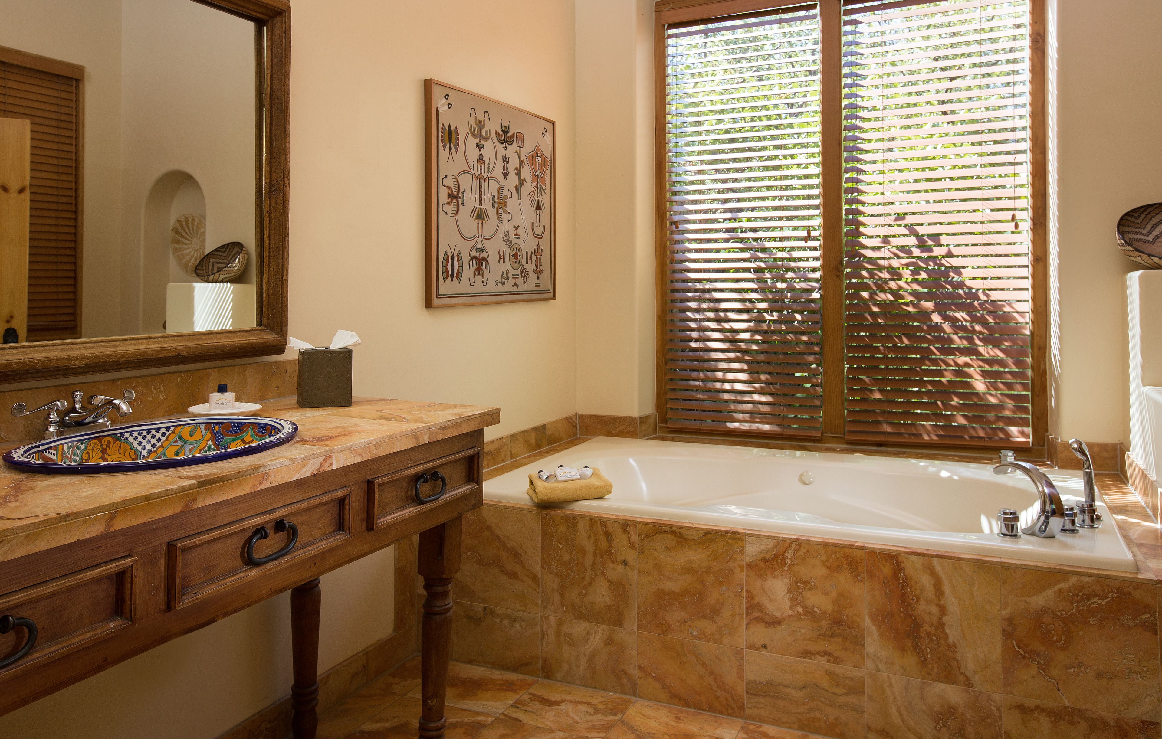 A bathroom with a marble sink, a bathtub, and a large mirror.