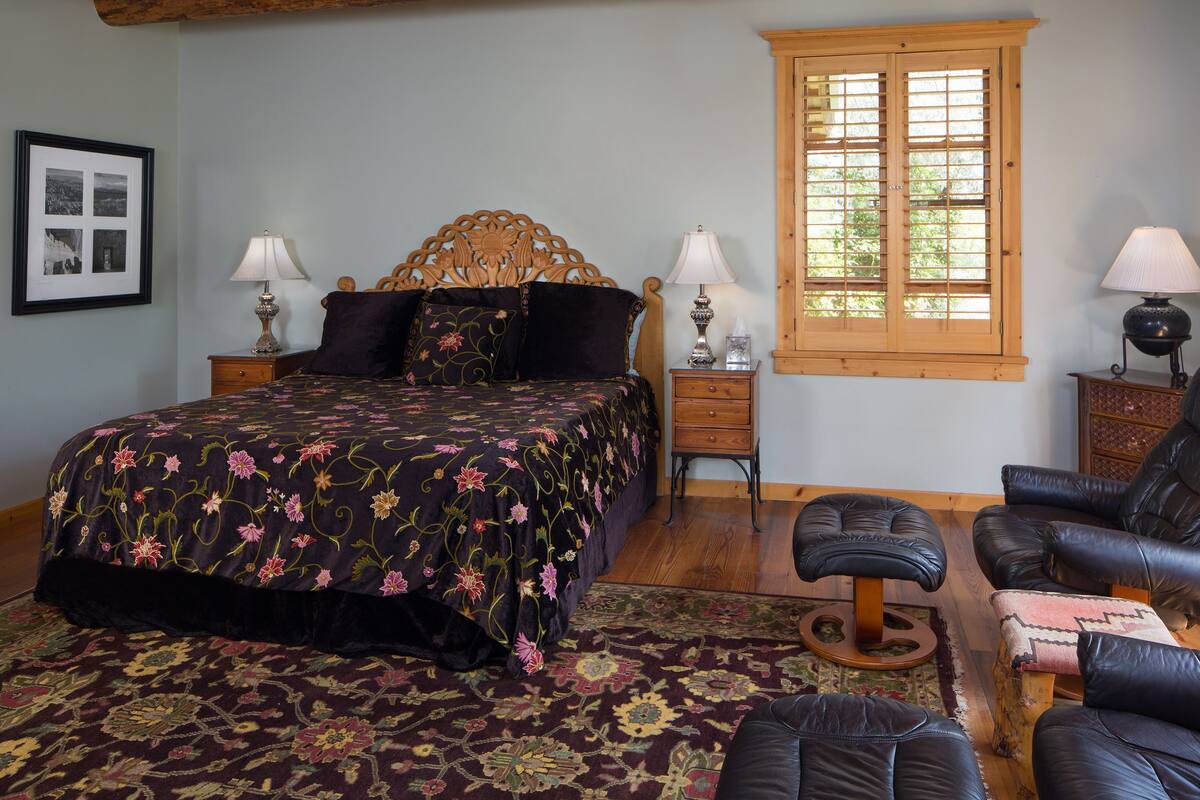 Une chambre avec un grand lit, deux tables de chevet, une fenêtre, une chaise et un tapis.